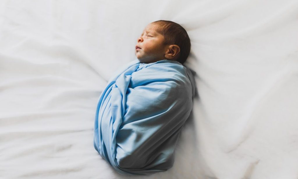 Pasgeboren baby rustgevend in babyslaapzak, veilig en warm ingepakt voor een goede nacht slaap